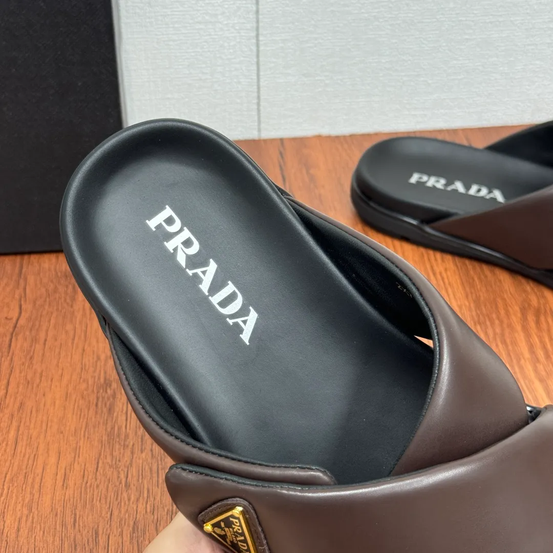 Batch 580 Prada/Prada's new men's leather cross slippers. Velcro closure can finely adjust the size. Calf leather light luxury slippers. Thick soft calf leather wraps the upper. Fat but soft rubber lazy style, soft and comfortable, excellent foot feel. Genuine leather bottom layer, cross style, with a Velcro closure buckle, easy to adjust the appropriate size, and a perfect fit for the wearing experience. The enamel gold triangle logo highlights the brand's classic features. Lightweight rubber thin sole, high foot comfort! Complete package! Size: 39-40-41-42-43-44-45 Leather shoe size Item number: 2X7132 Brown